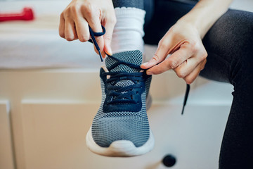 Attractive fit woman tying shoe laces at home