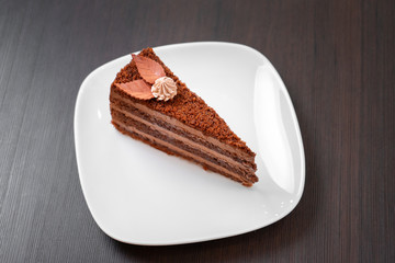 Chocolate cake on a white plate on a wooden table.