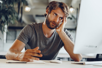 Bearded man freelancer using computer in a modern coworking place. Freelance business concept