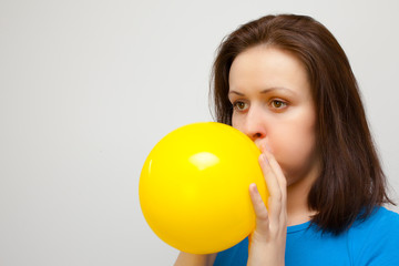 Fototapeta na wymiar beautiful woman is blowing up a yellow balloon