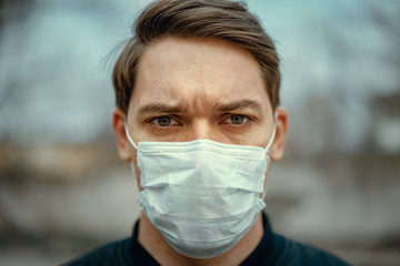 Portrait man in medical mask. Young man stands on light background and looking at camera.
