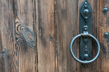 Old wooden doors. Iron rings on the gate. Decoration elements of buildings, vintage iron door handles, knockers and gong handle