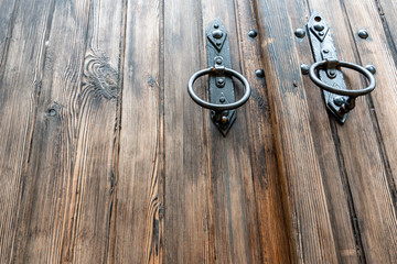 Old wooden doors. Iron rings on the gate. Decoration elements of buildings, vintage iron door handles, knockers and gong handle