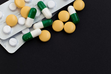 Pharmacy background on a black table. Tablets on a black background, pills. Medicine and healthy, close up of capsules.