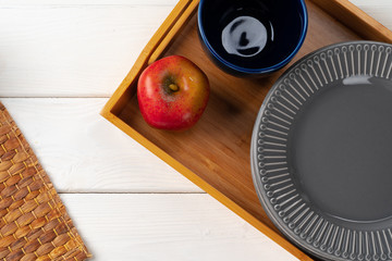 Glossy grey ceramic plate with cutlery on wooden kitchen table