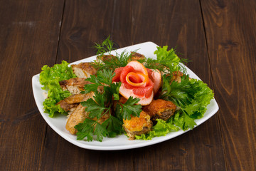 cooked meat mix of chicken wings and legs, chicken fillet with herbs and parsley, grapefruit on a white plate. wooden table background