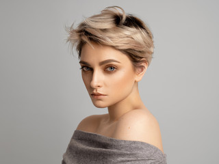 Sexy blonde woman with short hair posing in studio over gray background