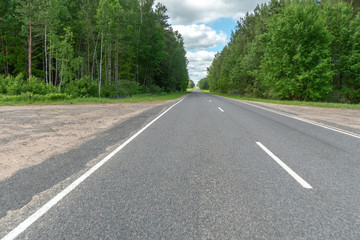 Fototapeta na wymiar Highway or asphalt road through the forest. An empty roadway with no cars or people. Travel to natural places or reserves. social distance. Absence of people. Coronavirus. COVID19