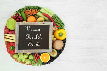 Vegan health food with plant based foods high in protein, omega 3, vitamins, minerals, anthocyanins, antioxidants, smart carbs & dietary fibre. On rustic wood with title on a blackboard.
