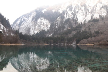 beautiful landscape of a lake in national park, Sichuan China with snow and reflection of the trees in the water