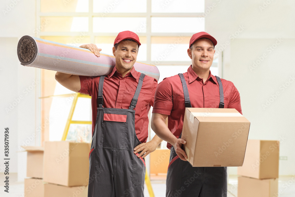 Wall mural Male workers holding a carpet and a cardboard box