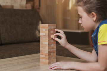 Children at home play the game Jenga and pull the blocks out of the tower so that it does not fall. Competition who will win. Spend time at home.
