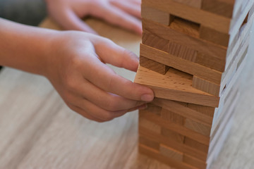 Children at home play the game of Jenga and pull out blocks from the tower so that it does not fall. Competition who will win. Spending time at home.