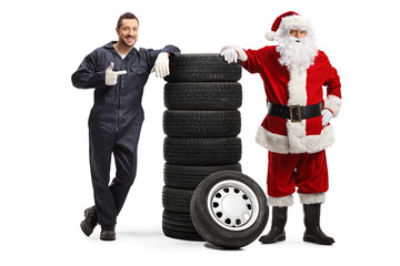 Auto mechanic pointing at a pile of tires and posing with Santa Claus