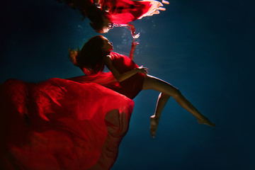 A woman underwater in a pool wrapped in cloth