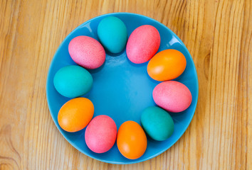 colored easter eggs on a blue plate on the table top view