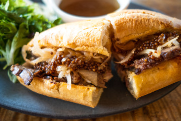 Pork sandwich with carmelized onion and whole mustard, au jus dipping sauce in back