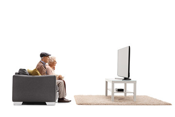 Profile shot of a senior man and woman sitting on a sofa and watching tv - Powered by Adobe
