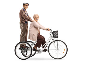 Senior man and woman riding on a tricycle