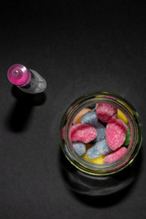 Container full of colored jelly beans after being injected with pink liquid