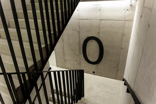 Huge zero floor sign in the staircase. Concrete walls and steel handrail