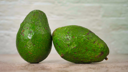 Des avocats sur une table avec un arrière plan en briques blanche