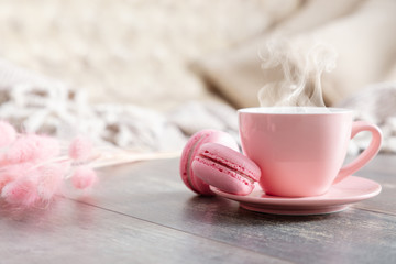 Cozy home composition. Steaming cup coffee or hot drink and macaroon on wooden white table. Front view, copy space