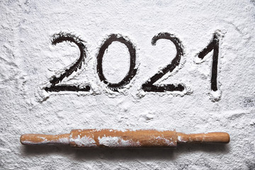 numbers 2021 paint handwritten on flour brown table and rolling pin