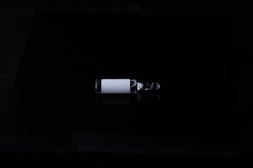 Ampoule with liquid inside, without the inscription on a label on a black background.