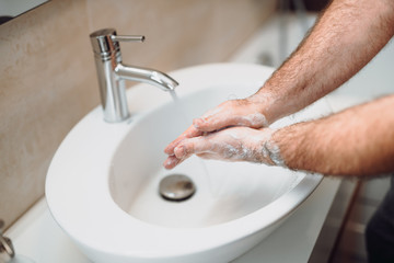 Caucasian man carefully washing hands with soap and sanitiser in home bathroom
