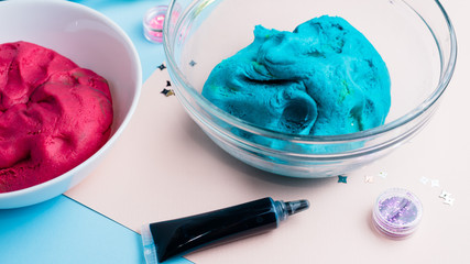 Homemade plasticine, plasticine, play dough on a colored background with glitters. Molding clay or slime. Homemade clay.