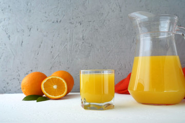 glass of orange juice and oranges on wooden table