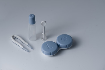 a contact lens kit consists of a container, a suction cup, tweezers and a small bottle for a lens solution
