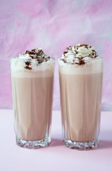 Chocolate milkshake with ice cream and whipped cream served in a glass cup. Summer drink. Food background. Pink background.