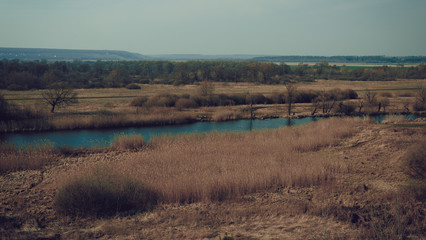 A quiet river in a green rural area. Beautiful landscape with a river with calm water, located next to a spring forest in nature. A narrow, winding river that runs through a grove of trees.