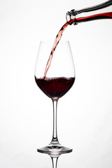 Silhouette of a wine glass, wine and grape juice is poured from a bottle, against a white background with reflection in Zurich, Europe, Switzerland.