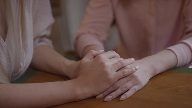 Handheld shot with close up of unrecognizable young woman putting her hands on top of her mothers hands