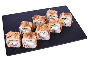 Traditional fresh japanese sushi rolls on a black stone Teka Kaji on a white background. Roll ingredients: fried salmon, philadelphia cheese, cucumber, tuna chips, nori, rice.