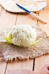 Cauliflower on wooden background. Head of cauliflower on the burlap. Organic food. Rustic style