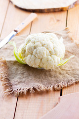 Cauliflower on wooden background. Head of cauliflower on the burlap. Organic food. Rustic style