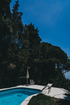 Piscina con sombrilla en bosque con &aacute;rboles

