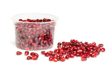 Red juicy pomegranate fruit seeds in in plastic box / package container isolated on white...