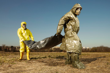 Team in protection suits pick up unknown victim of disease covid-19