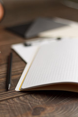 Close-up of a black tablet with a sheet of notepads and glasses with coffee on a wooden table with a blurred background. office Desk concept.