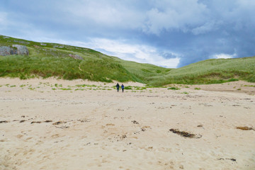 Ein Mann und eine Frau laufen in den Dünen entlang