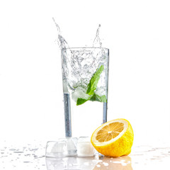 mojito cocktail drink or water with mint and lemon in a glass splash splashing out of a glass with ice cubes, drops and splashes isolated on white background