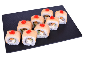 Traditional fresh japanese sushi rolls on a black stone Mikado on a white background. Roll ingredients: mussels, escolar fish, izumi perch fish, philadelphia cheese, red tobiko, nori, rice.
