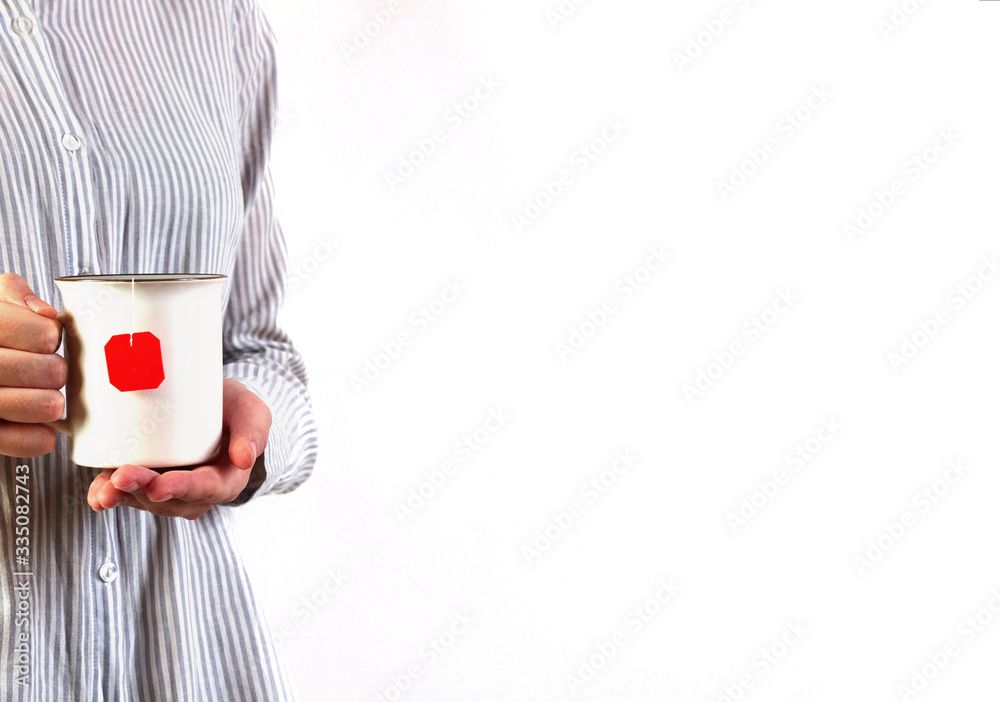 Wall mural Woman in blue shirt holding white cup of tea with two hands. Copyspace, close up