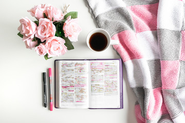 Pink Bible flat lay: Bouquet of pink roses, open Bible, black tea, coffee, journal, notebook, pen and pink blankets. Morning devotional. Rose, white, grey tones. Baselland, Switzerland - 02.04.2020 - Powered by Adobe