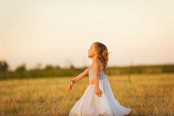 Fototapeta na wymiar happy kid girl grey dress run on wheat field